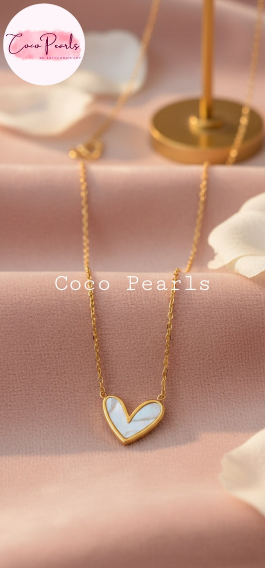 Coco Pearls Stainless Steel Anti Tarnish  heart of elegance and Gold necklace with a white heart-shaped pendant on a pink background