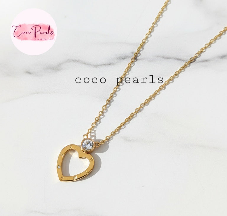Coco Pearls Stainless Steel Anti Tarnish Gold heart sparkle necklace. heart-shaped pendant necklace with a diamond on a marble background