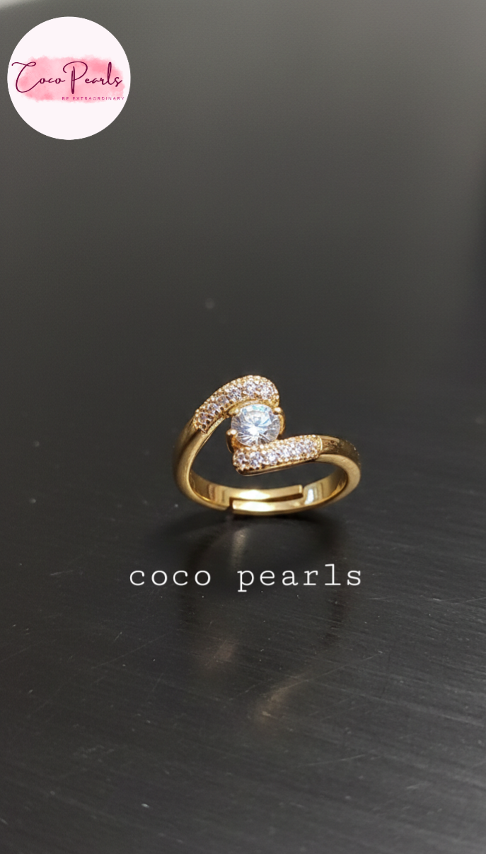 coco pearls stainless steel anti tarnish gold heart spark ring diamond studded with a big diamond in center displayed on metallic surface