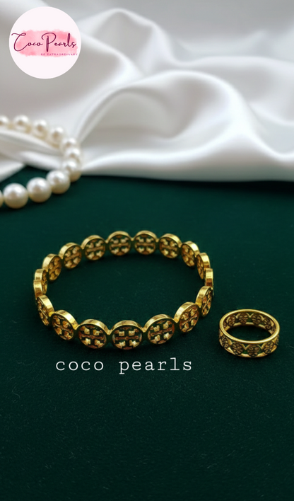 coco pearls stainless steel anti tarnish gold interlocking logo handcuff and ring with all over logos connected displayed on a velvet cloth