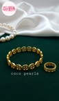 coco pearls stainless steel anti tarnish gold interlocking logo handcuff and ring with all over logos connected displayed on a velvet cloth