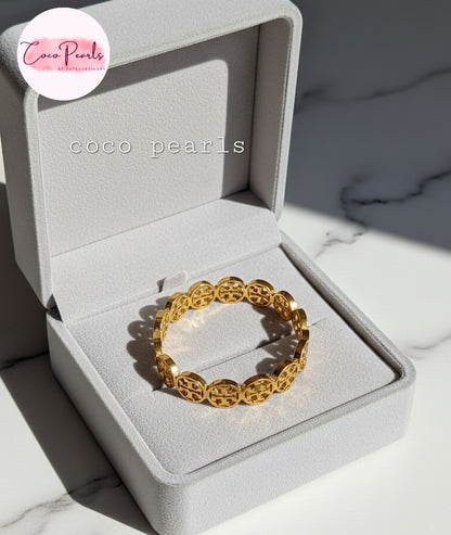coco pearls stainless steel anti tarnish gold interlocking logo handcuff with all over logos connected displayed on a jewelry box