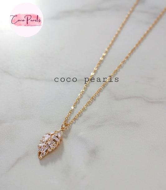 Coco Pearls Stainless Steel Anti Tarnish Gold leaf of light necklace with a diamond leaf shape pendant on a marble background
