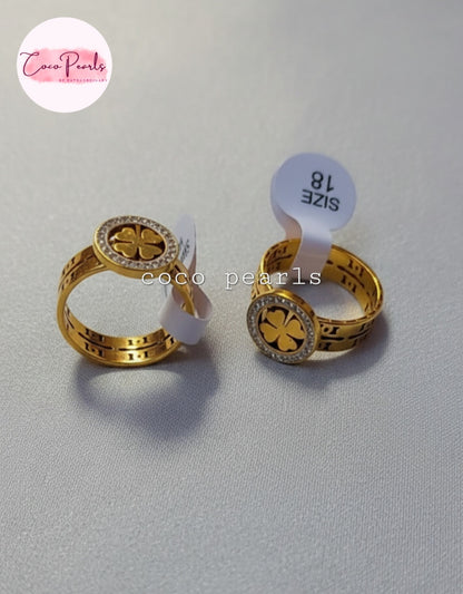 Coco Pearls Stainless Steel Anti Tarnish Gold luck charm ring with gemstones studded clover charm on a gold band on a simple background