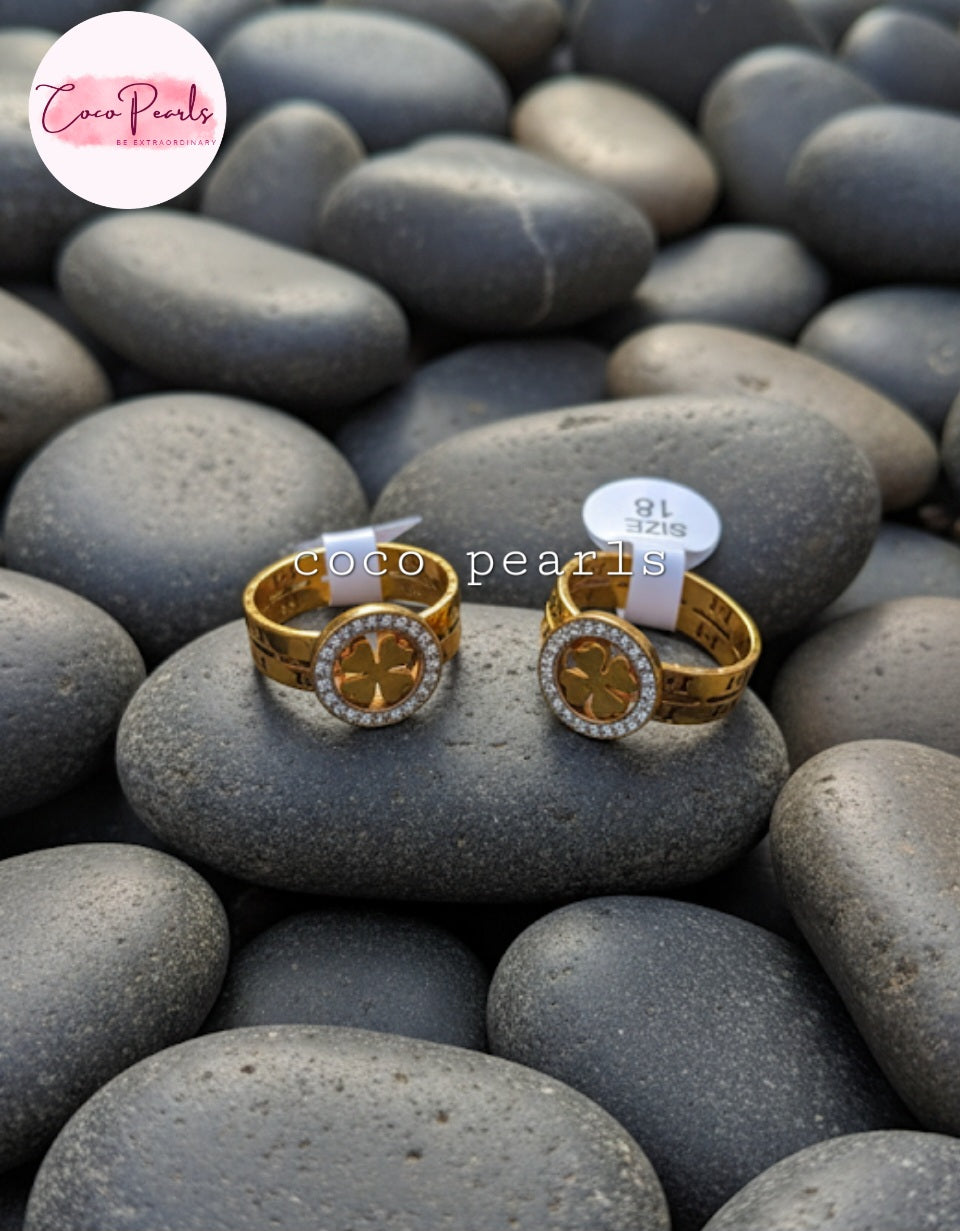 Coco Pearls Stainless Steel Anti Tarnish Gold luck charm ring with gemstones studded clover charm on a gold band on a rock surface