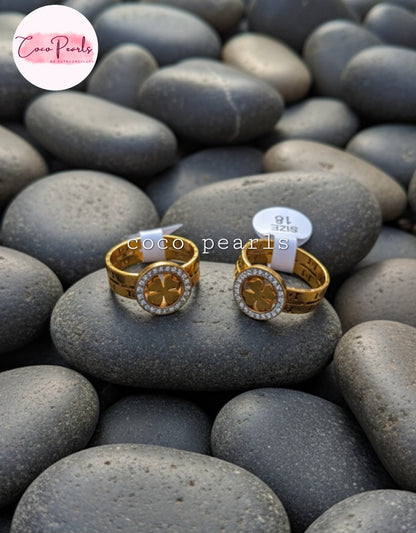 Coco Pearls Stainless Steel Anti Tarnish Gold luck charm ring with gemstones studded clover charm on a gold band on a rock surface