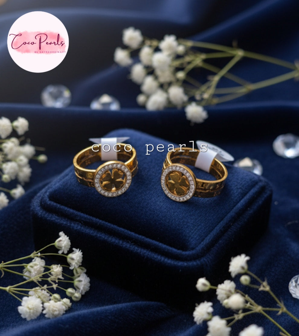 Coco Pearls Stainless Steel Anti Tarnish Gold luck charm ring with gemstones studded clover charm on a gold band on a blue background