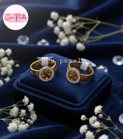 Coco Pearls Stainless Steel Anti Tarnish Gold luck charm ring with gemstones studded clover charm on a gold band on a blue background
