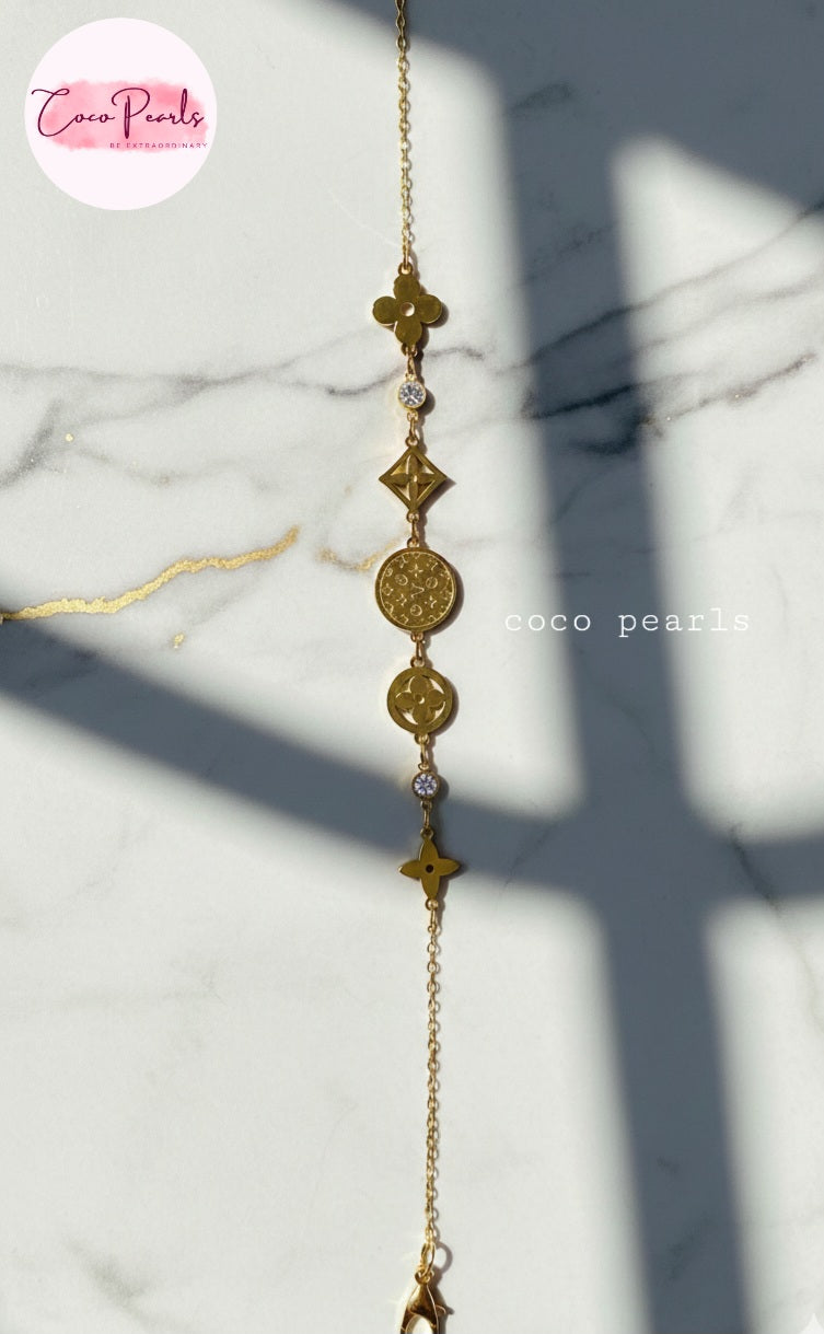 coco pearls stainless steel anti tarnish Gold lucky charm bracelet with intricate designs on a marble background