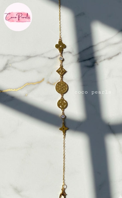 coco pearls stainless steel anti tarnish Gold lucky charm bracelet with intricate designs on a marble background