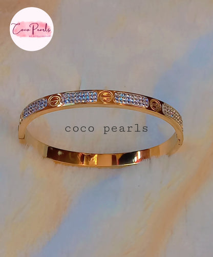 Coco Pearls Stainless Steel Anti Tarnish Gold lucky charm bangle bracelet with diamonds on a light background
