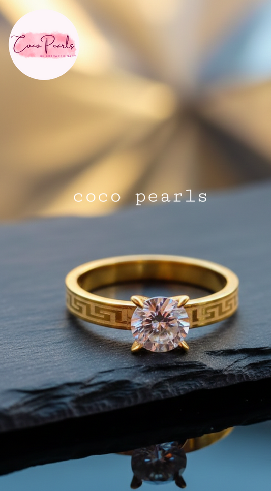 coco pearls stainless steel anti tarnish Gold luminous solitaire ring with a clear gemstone on a dark surface