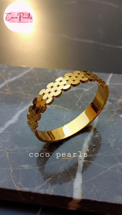coco pearls stainless steel anti tarnish gold luxury disc wrap handcuff bangle bracelet displayed on marble surface