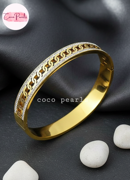 coco pearls stainless steel anti tarnish Gold luxury chai bangle handcuff diamond studded white stones on a dark surface