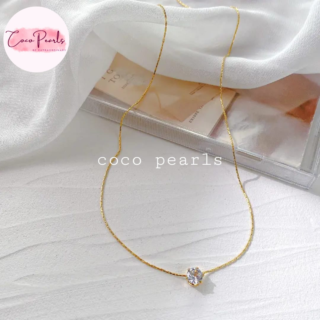 Coco Pearls Stainless Steel Anti Tarnish Gold milestone necklace  with a diamond pendant on a white fabric background