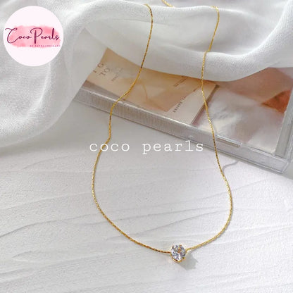 Coco Pearls Stainless Steel Anti Tarnish Gold milestone necklace  with a diamond pendant on a white fabric background