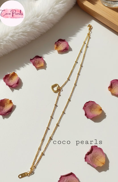 Coco Pearls Stainless Steel Anti Tarnish Gold minimal love anklet  with heart-shaped pendant on a light surface with pink petals