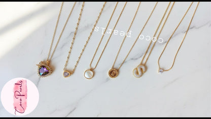 Coco Pearls Stainless Steel Anti Tarnish Gold necklaces with various pendants on a white marble surface