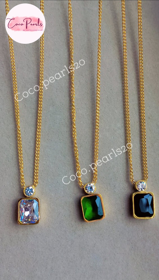 Coco Pearls Stainless Steel Anti Tarnish  onyx obsession necklaces Three gold necklaces with green, clear ad black rectangular gemstone with a round small gemstone on stone on top on a gray background