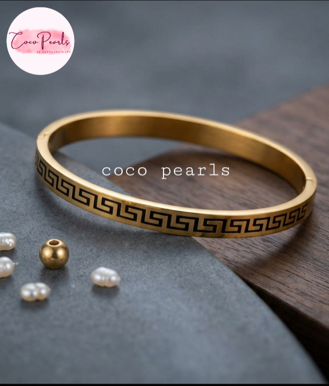 Coco Pearls Stainless Steel Anti Tarnish Gold pattern charm handcuff bracelet with black pattern on a white marble surface