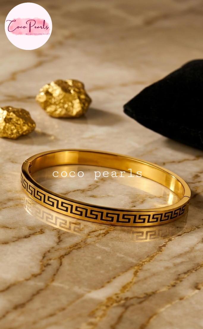 Coco Pearls Stainless Steel Anti Tarnish Gold pattern charm handcuff bracelet with black pattern on a white marble surface