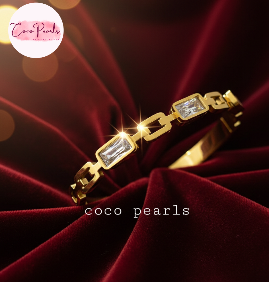 coco pearls stainless steel anti tarnish Gold radiant cube handcuff bangle  bracelet with clear stones on a red fabric background