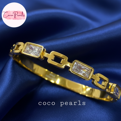 coco pearls stainless steel anti tarnish Gold radiant cube handcuff bangle  bracelet with clear stones on a blue satin