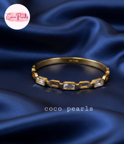 coco pearls stainless steel anti tarnish Gold radiant cube handcuff bangle  bracelet with clear stones on a blue background