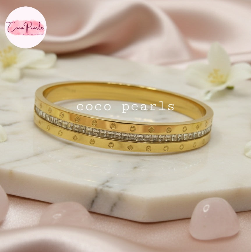 Coco Pearls Stainless Steel Anti tarnish gold radiant spark handcuff bangle bracelet with diamond accents on marble surface