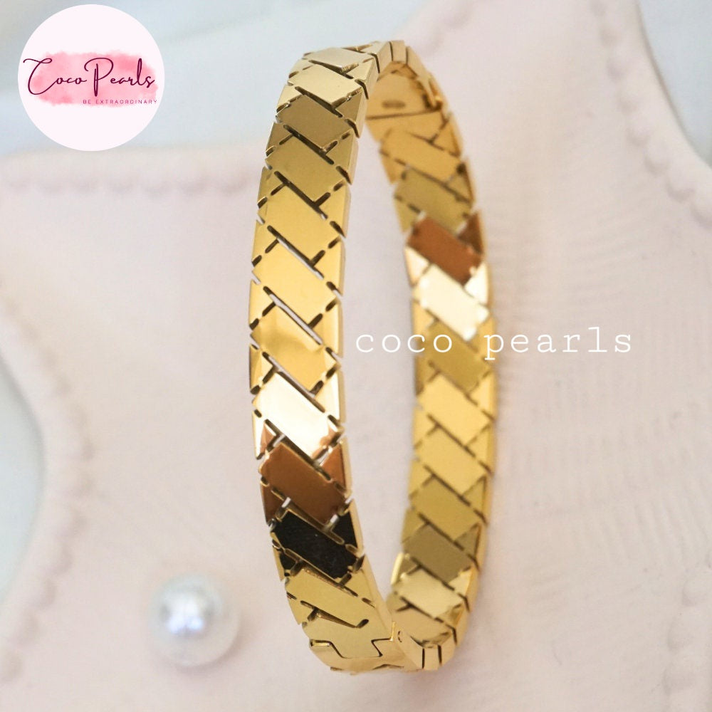 Coco pearls stainless Steel anti tarnish gold regal grid handcuff displayed on simple background 