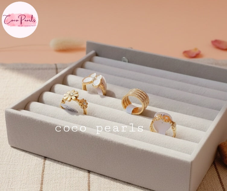 Coco Pearl stainless steel Anti tarnish  Set of gold rings in jewelry box on a beige surface.