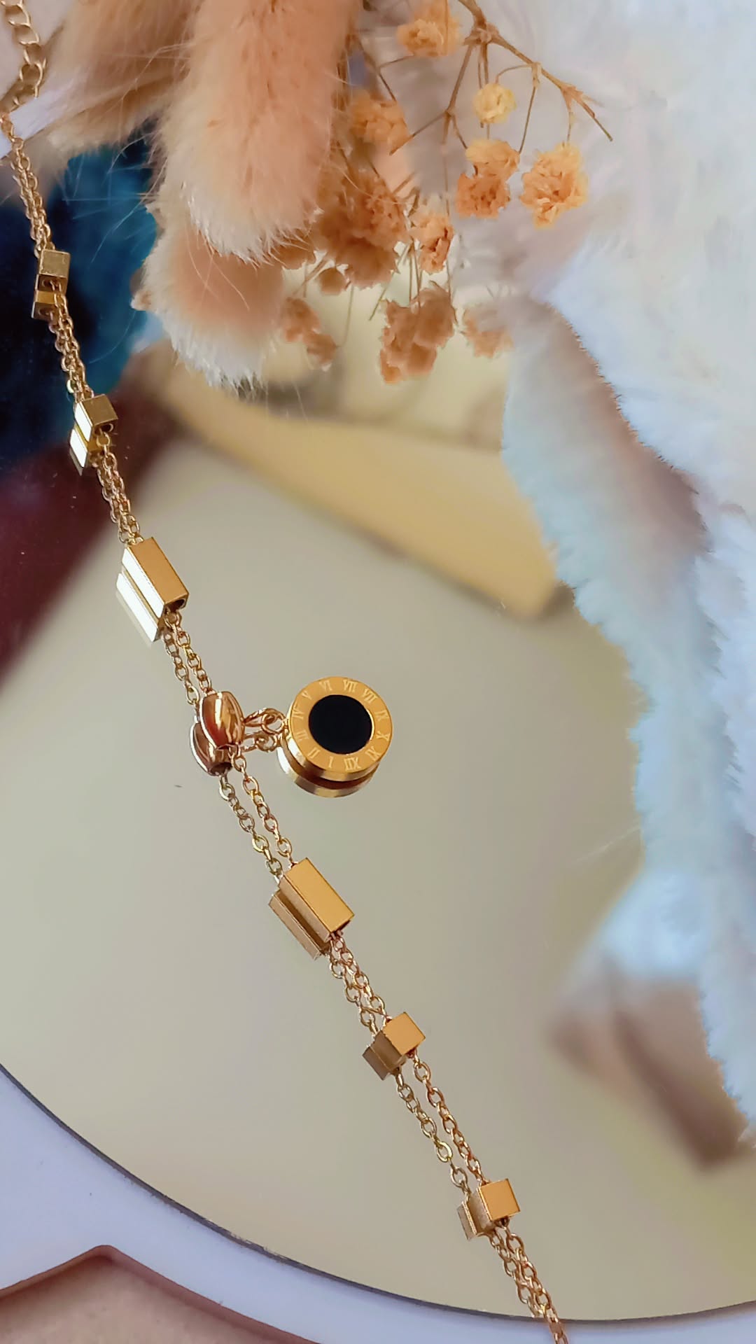 Coco Pearls Stainless steel anti tarnish Gold roman accent geometry bracelet with black gemstone hanging displayed on a marble background,