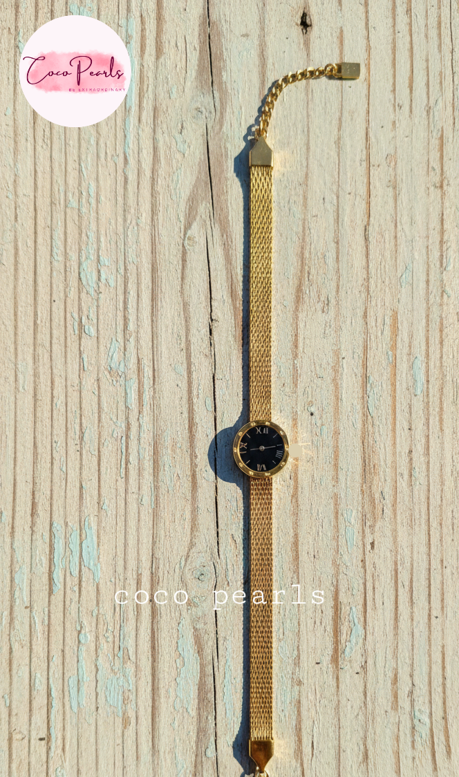 Coco Pearls Stainless steel Ani Tarnish Gold roman fake watch mesh bracelet with a black fake watch center displayed on a wooden background