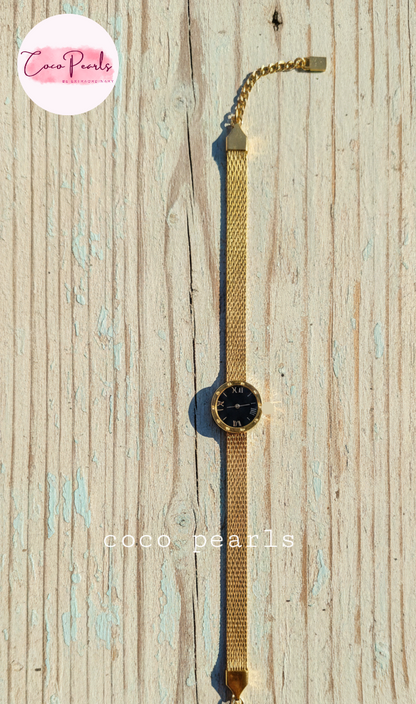 Coco Pearls Stainless steel Ani Tarnish Gold roman fake watch mesh bracelet with a black fake watch center displayed on a wooden background