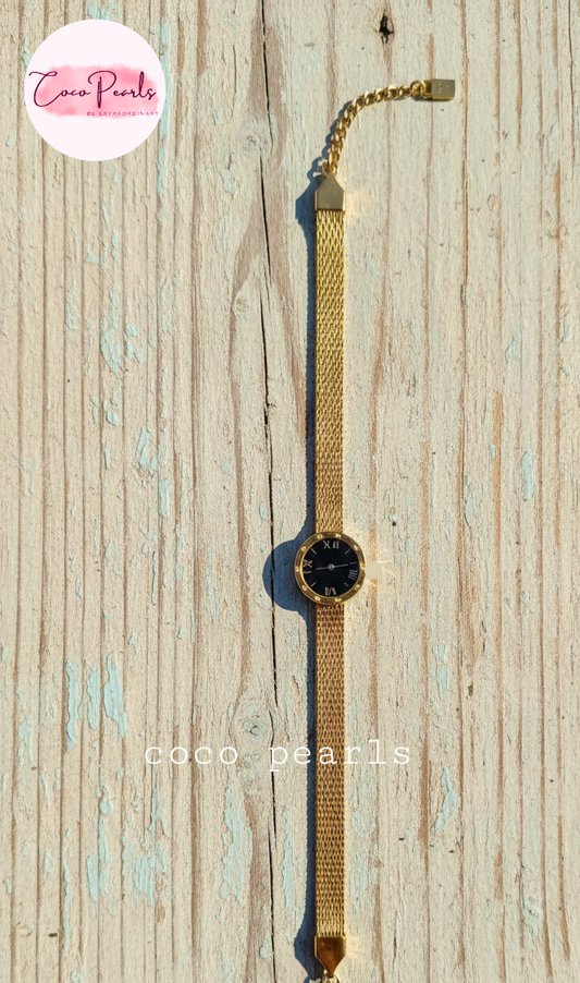 Coco Pearls Stainless steel Ani Tarnish Gold roman fake watch mesh bracelet with a black fake watch center displayed on a wooden background