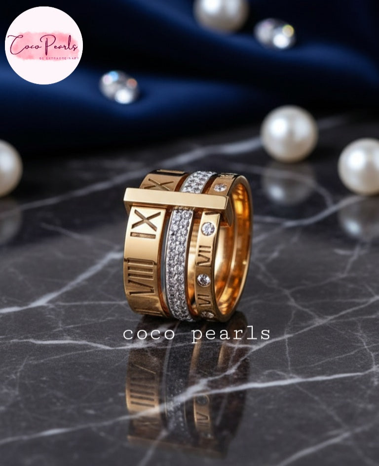 Coco Pearls Stainless Steel Anti Tarnish Gold roman ring with Roman numeral design band, diamond band and roman diamond band on a dark marble surface