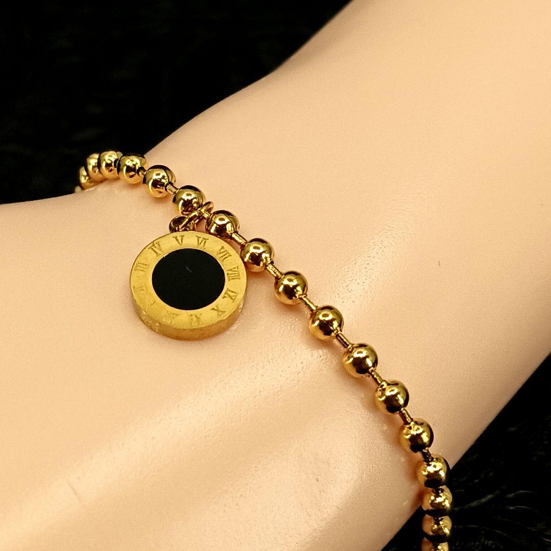 Coco Pearls Stainless Steel Anti tarnish Golden roman bead bracelet with bead chain and double sided roman hanging charm. one side white one side black. displayed on hand