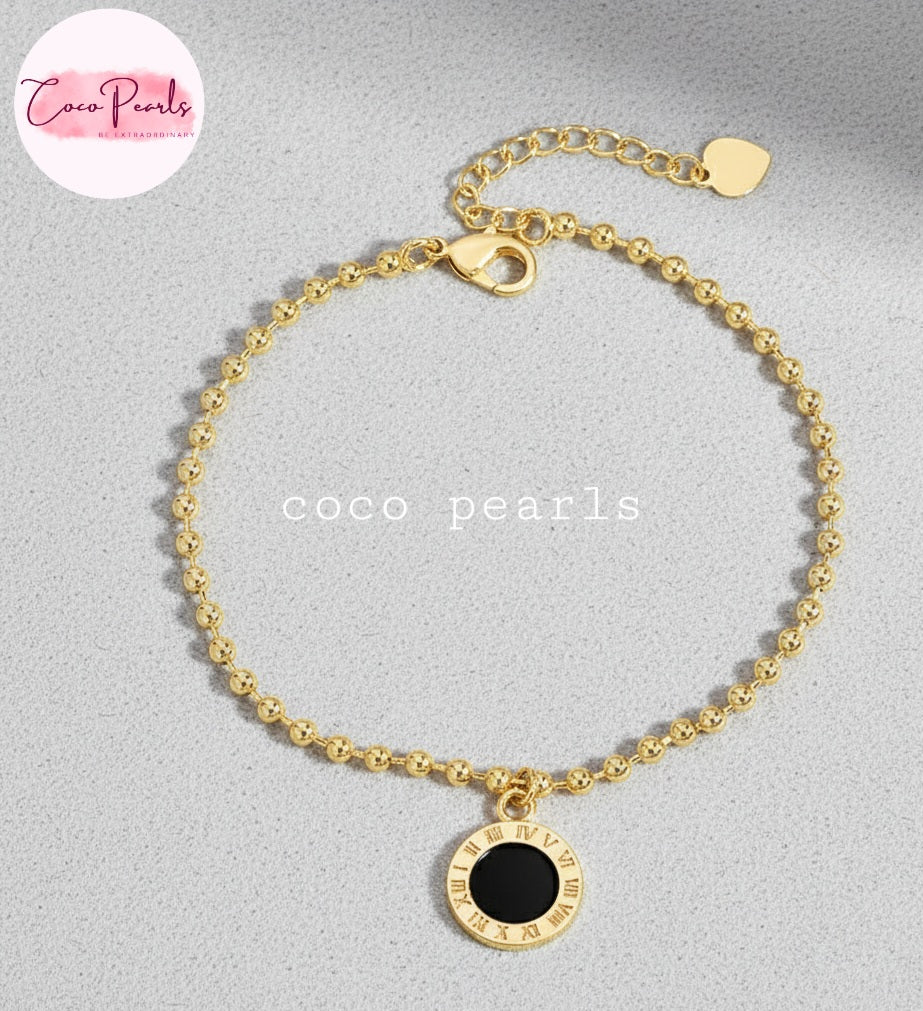 Coco Pearls Stainless Steel Anti tarnish Golden roman bead bracelet with bead chain and double sided roman hanging charm. one side white one side black. displayed on grey background