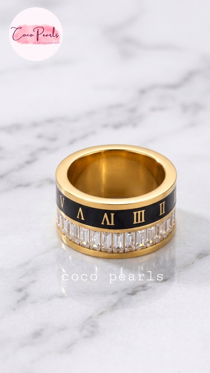 Coco pearls stainless Steel anti tarnish Gold roman empire ring with black band featuring Roman numerals and clear stones on a marble background