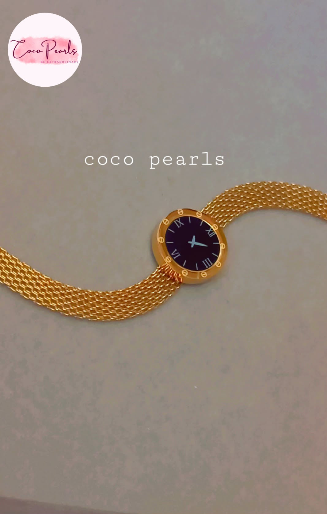 Coco Pearls Stainless steel Ani Tarnish Gold roman fake watch mesh bracelet with a black fake watch center displayed on a grey background