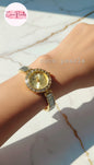 coco pearls Gold watch with rhinestone accents on a wrist against a marble background.