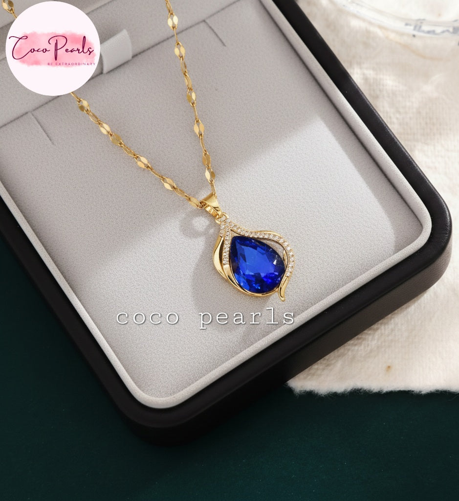coco pearls stainless steel anti tarnish Gold sapphire tear drop necklace with a sapphire blue teardrop pendant on a jewelry box
