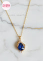 coco pearls stainless steel anti tarnish Gold sapphire tear drop necklace with a sapphire blue teardrop pendant on a marble background