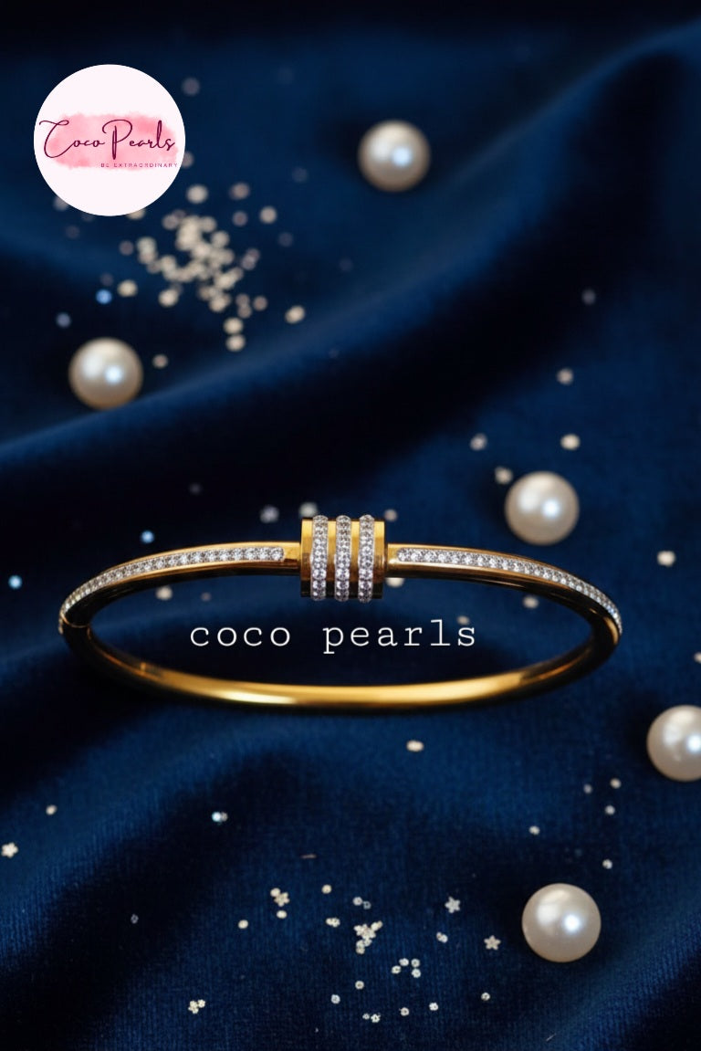 coco pearls stainless steel anti tarnish gold shimmering crown diamond studded handcuff displayed on blue fabric