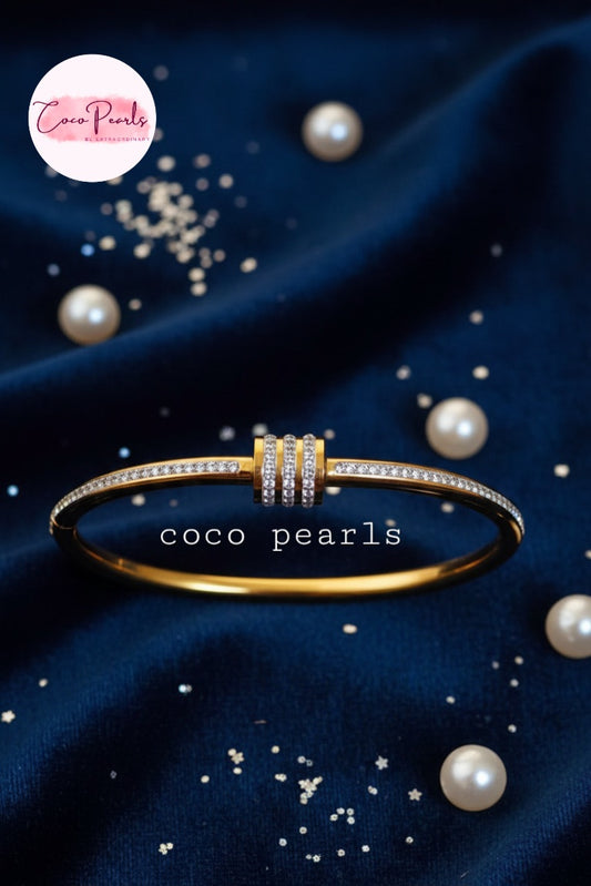 coco pearls stainless steel anti tarnish gold shimmering crown diamond studded handcuff displayed on blue fabric