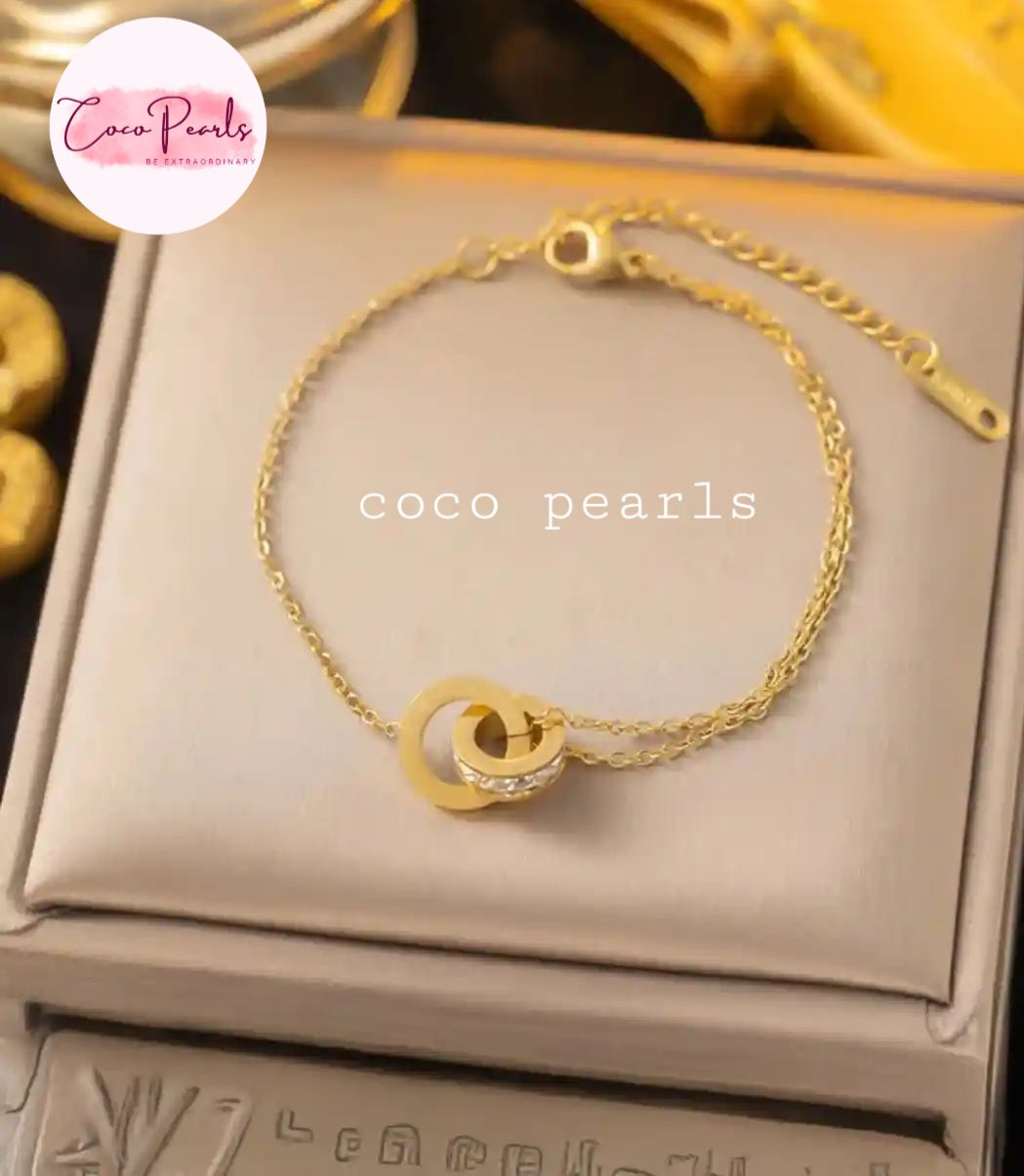 Coco Pearls Stainless Steel Anti tarnish Gold sparkle loop bracelet on a beige pillow 