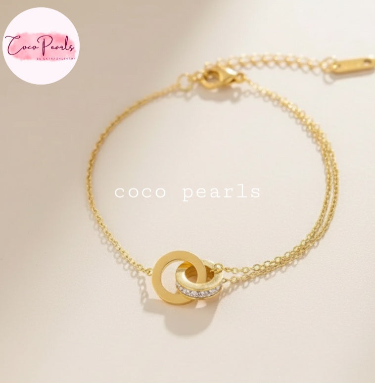 Coco Pearls Stainless Steel Anti tarnish Gold sparkle loop bracelet with interlocking circles on a lsimple background