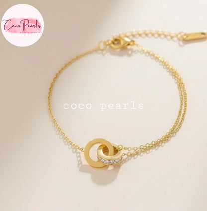 Coco Pearls Stainless Steel Anti tarnish Gold sparkle loop bracelet with interlocking circles on a lsimple background