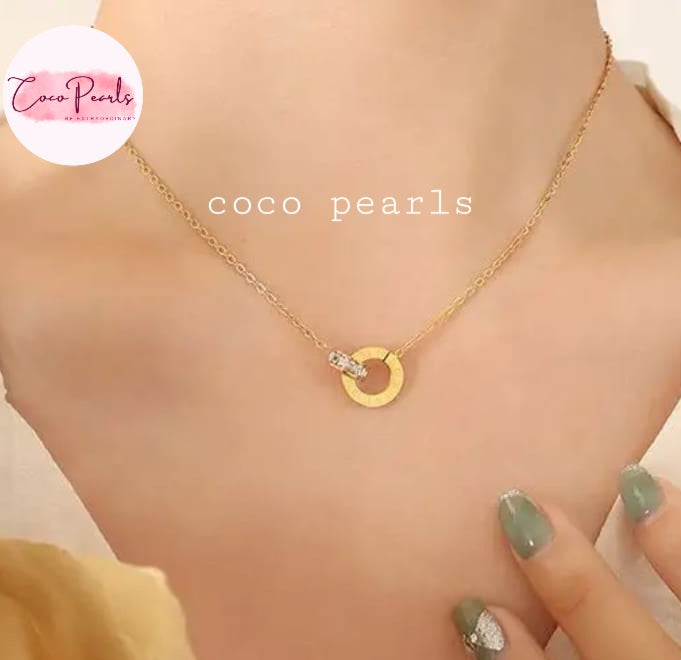Coco Pearls Stainless Steel Anti tarnish Gold sparkle loop jewelry with diamond studded necklace, with a circular pendant on a person's neck