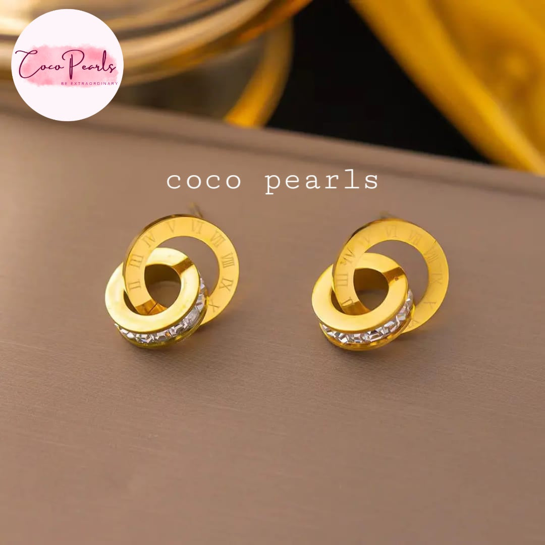 Coco Pearls Stainless Steel Anti tarnish Gold sparkle loop jewelry with diamond studded earrings with interlocking circles on a brown surface